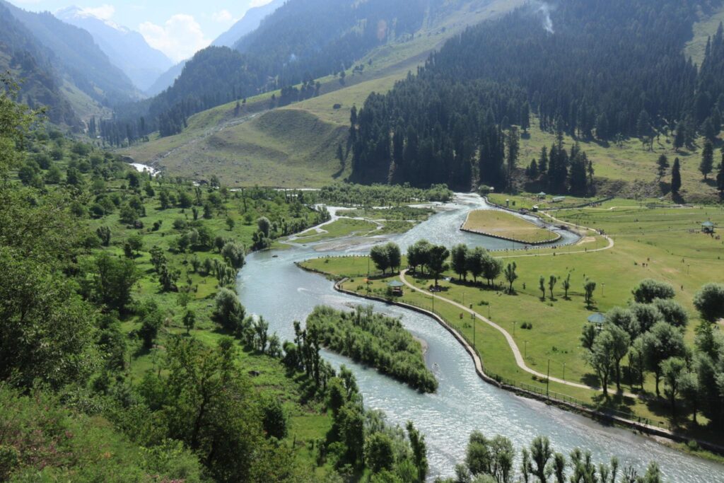 Aru Valley near Pahalgam Kashmir with green meadows, river and Himalayan mountains.